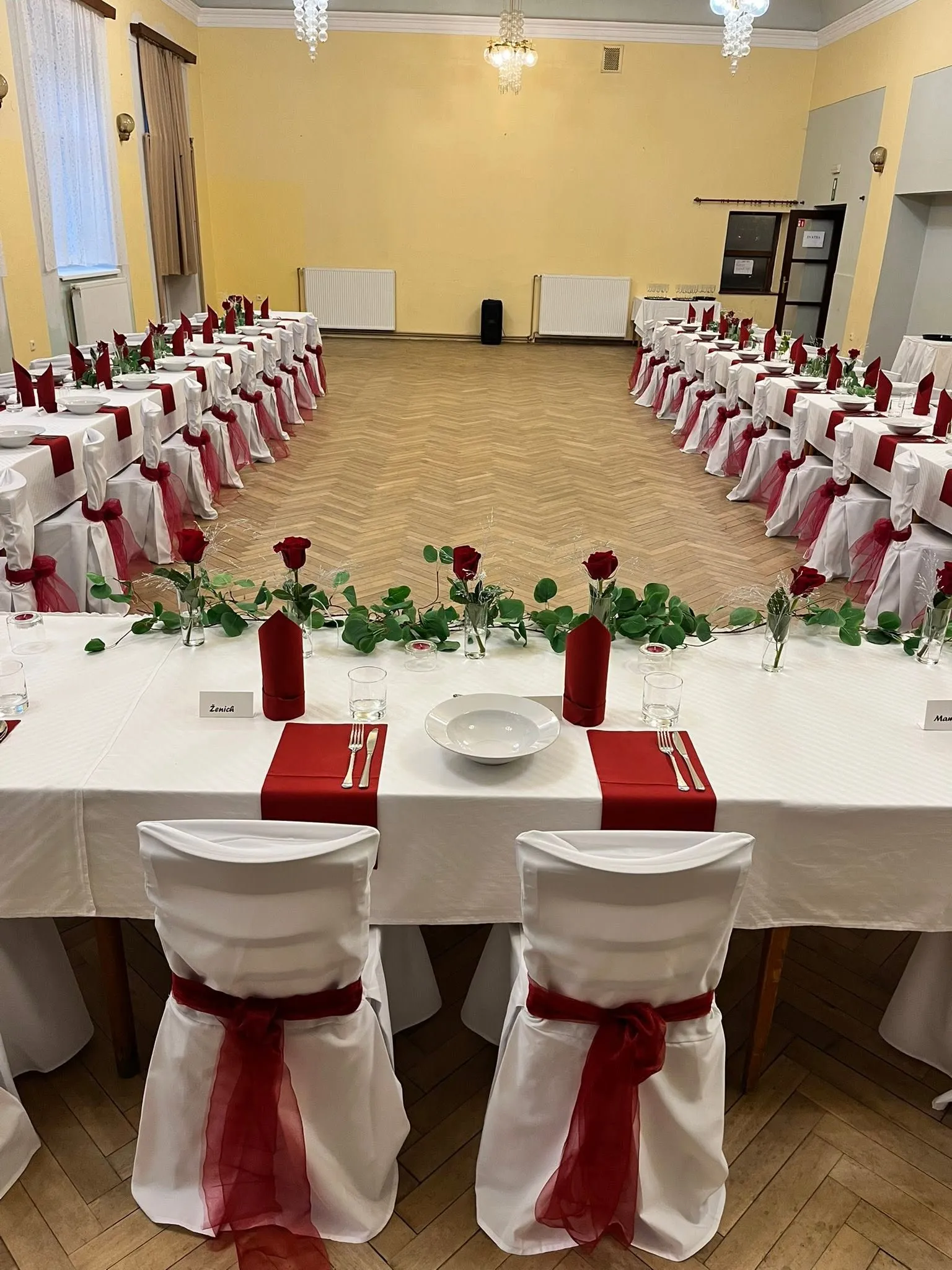 Detail svatební tabule s rudými růžemi, eukalyptem a jmenovkami